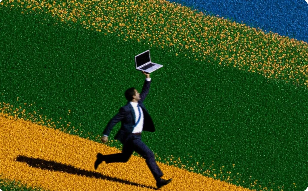 Man running across a field holding a laptop
